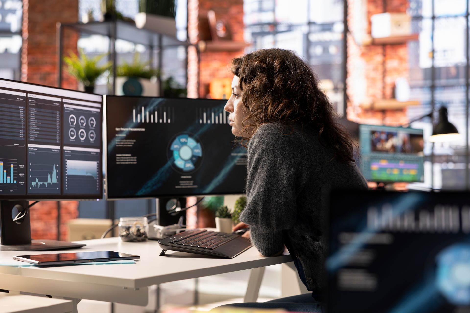 A woman is sitting at a desk looking at a computer screen.
