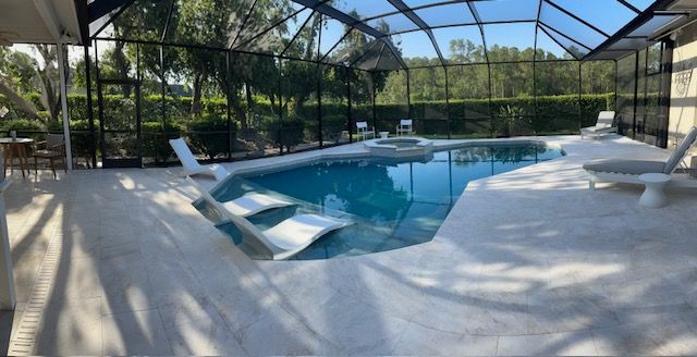 There is a large swimming pool with marble pool deck and screen enclosure.