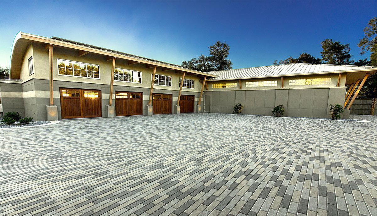 A large house with a lot of garages and a brick driveway in front of it.