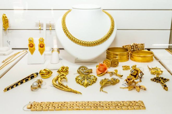 Gold jewelry set displayed on a white background, including necklace, earrings, rings, and bracelets