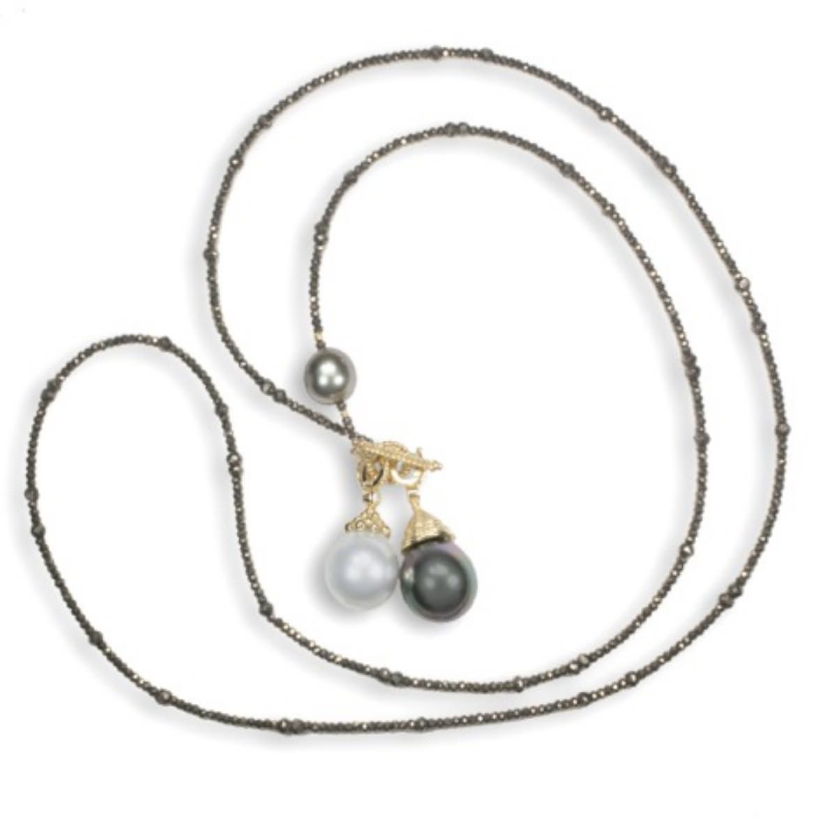 Long silver necklace with small charms and two dangling pearl-like pendants on a white background