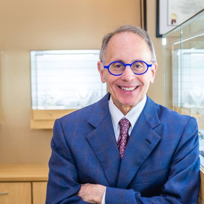 Smiling man in a blue suit and glasses standing in an office