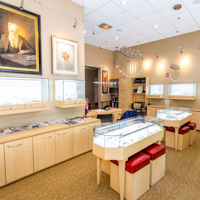 Jewelry store interior with glass display cases, red stools, and framed art on beige walls