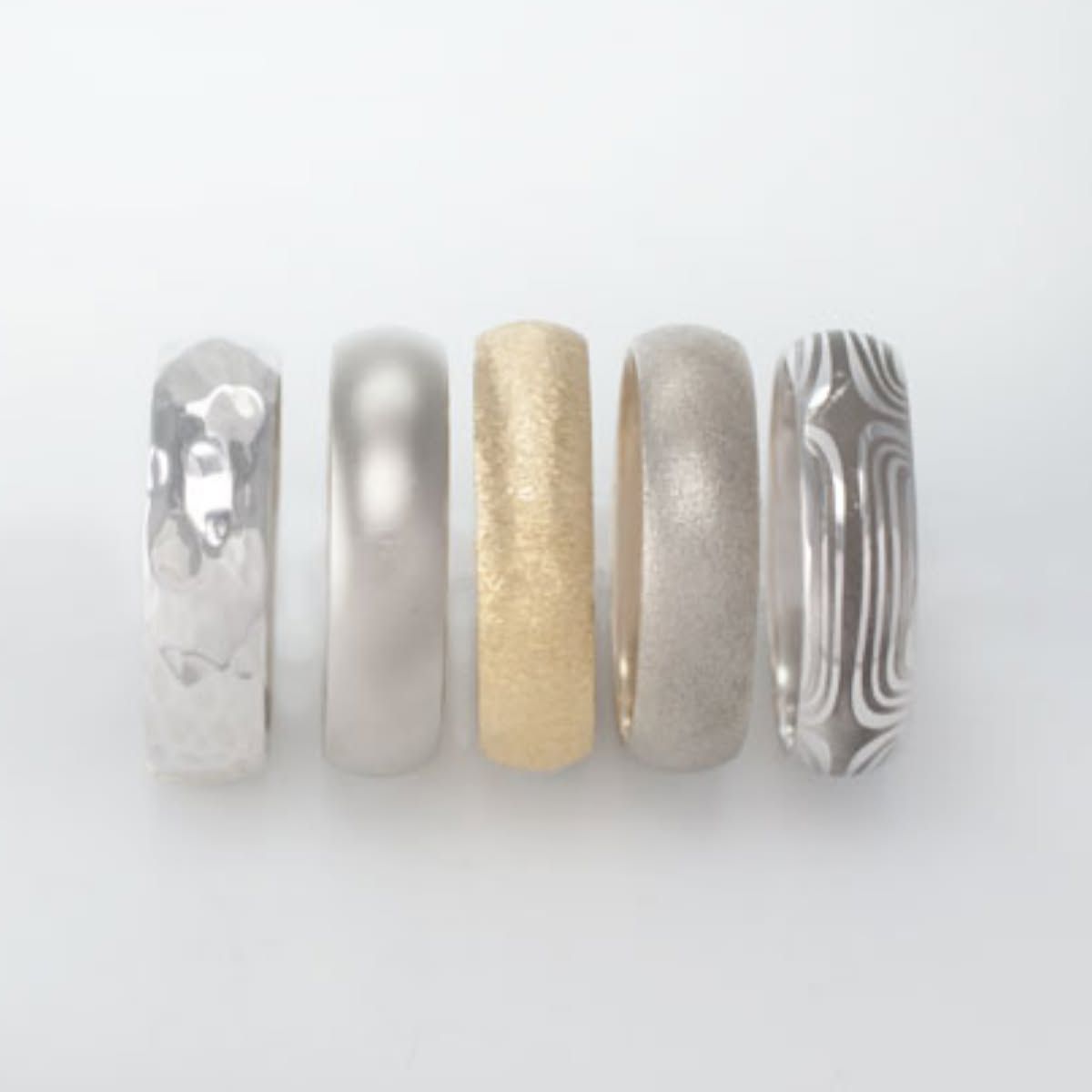 Five metallic and marble-patterned nail art swatches on a white background