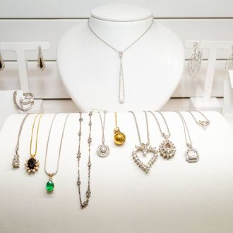 Jewelry display with silver necklaces and earrings on white busts and stands, including gold and gemstone accents