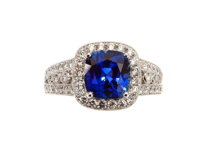 Silver ring with a square blue gemstone and small clear stones on a white background