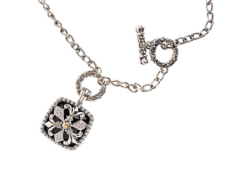 Silver necklace with a black floral pendant and matching circular charm on a white background