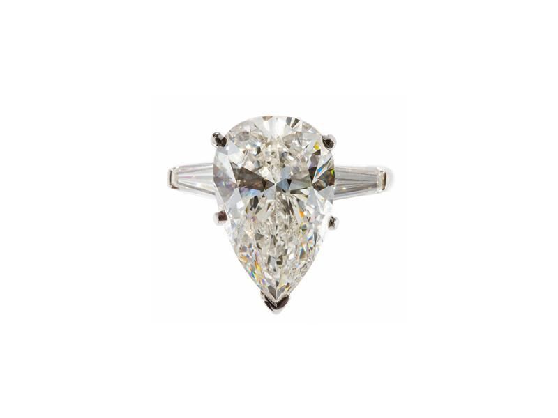 Pear-shaped diamond ring with a thin silver band on a white background