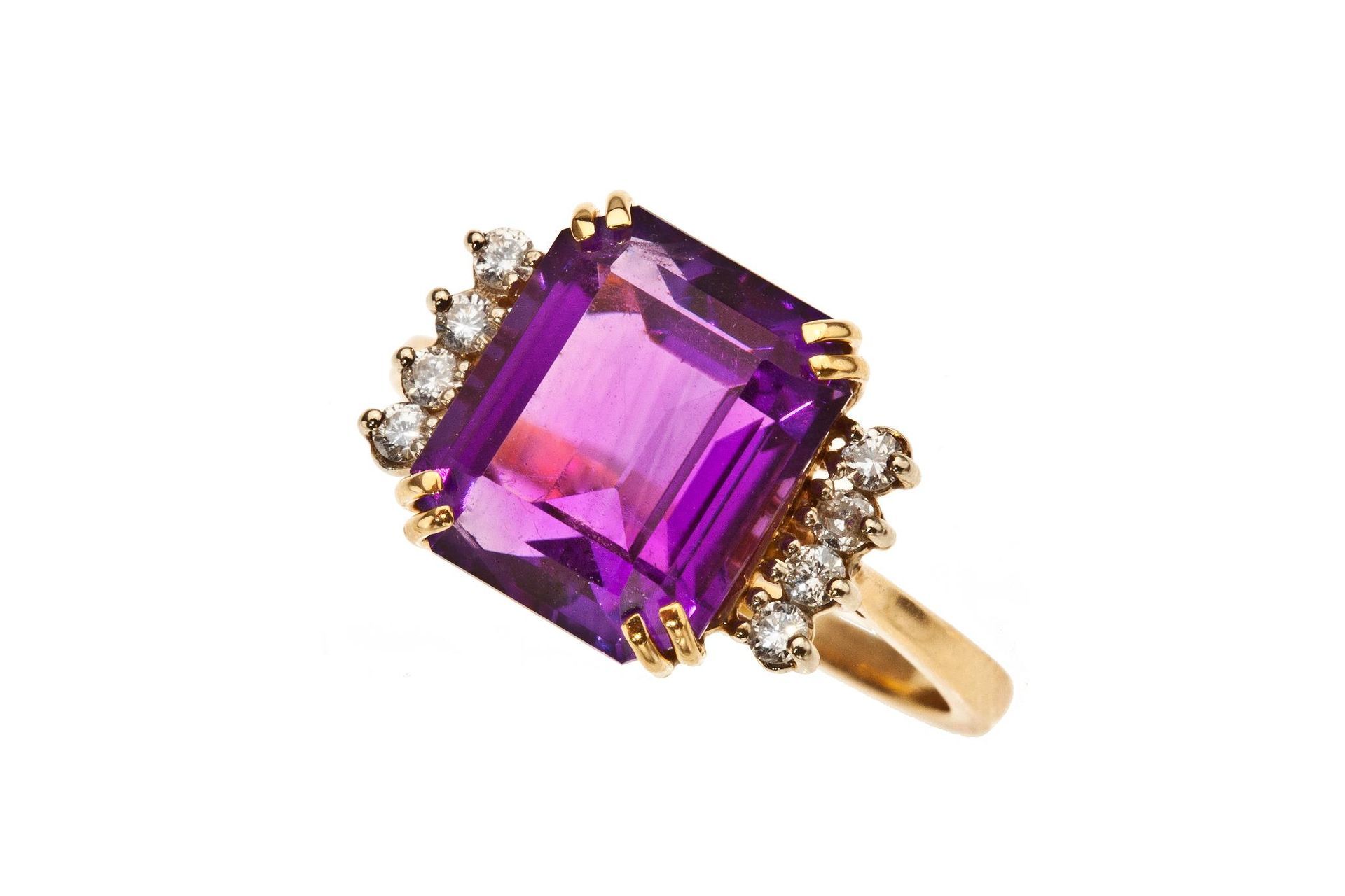 Gold ring with a large purple gemstone and small clear stones on a white background