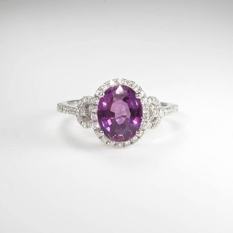Silver ring with a purple oval gemstone and small clear stones on a white background