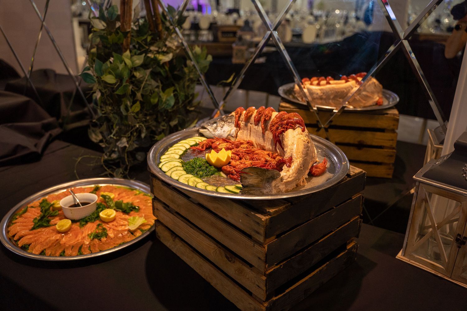 Buffettafel met opgemaakte visgerechten en kleurrijke garnituren in een sfeervol verlichte evenementenruimte.