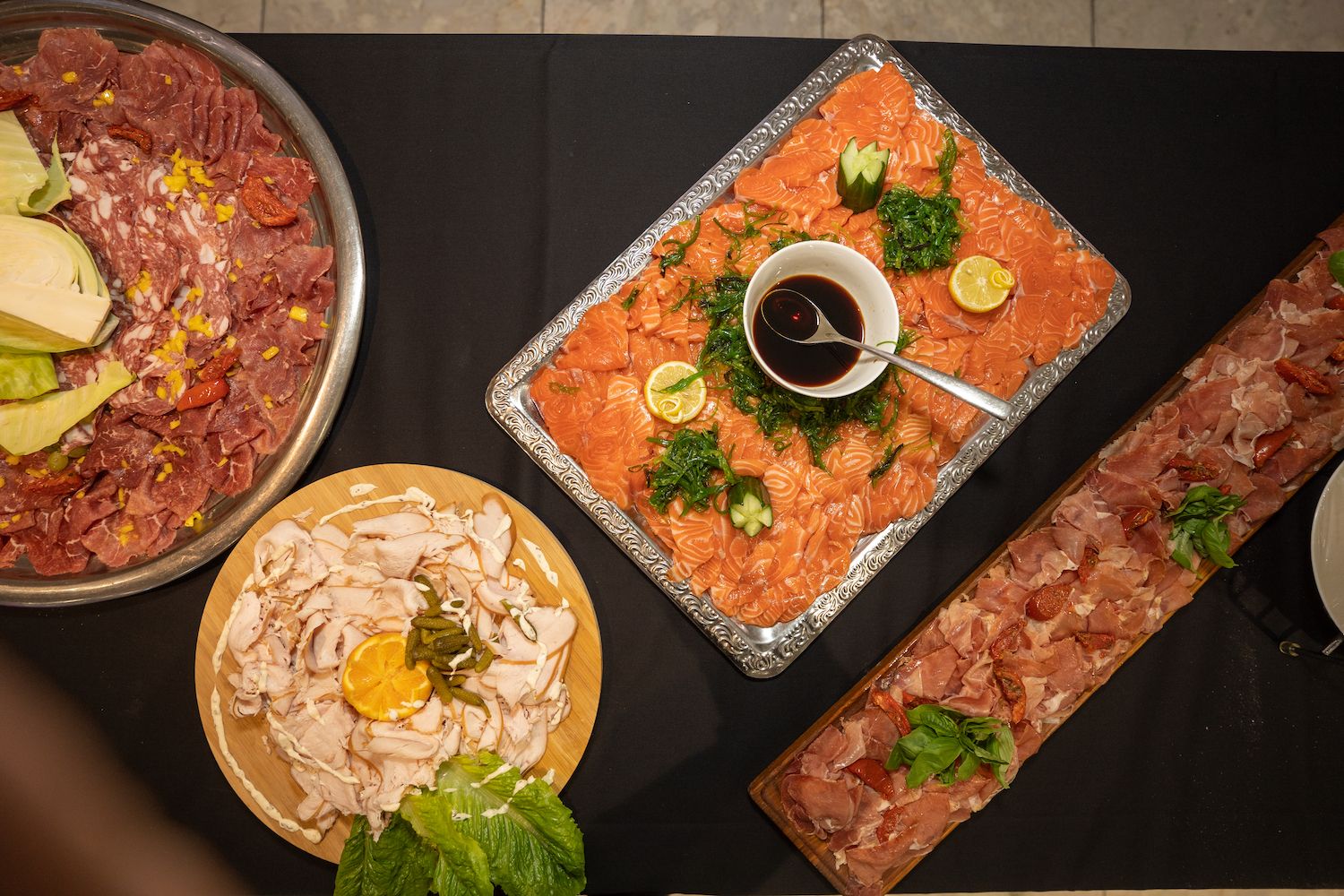 Diverse Aziatische gerechten op een zwart tafelblad, waaronder sushi, salade en dipsauzen, gerangschikt op borden en schalen.