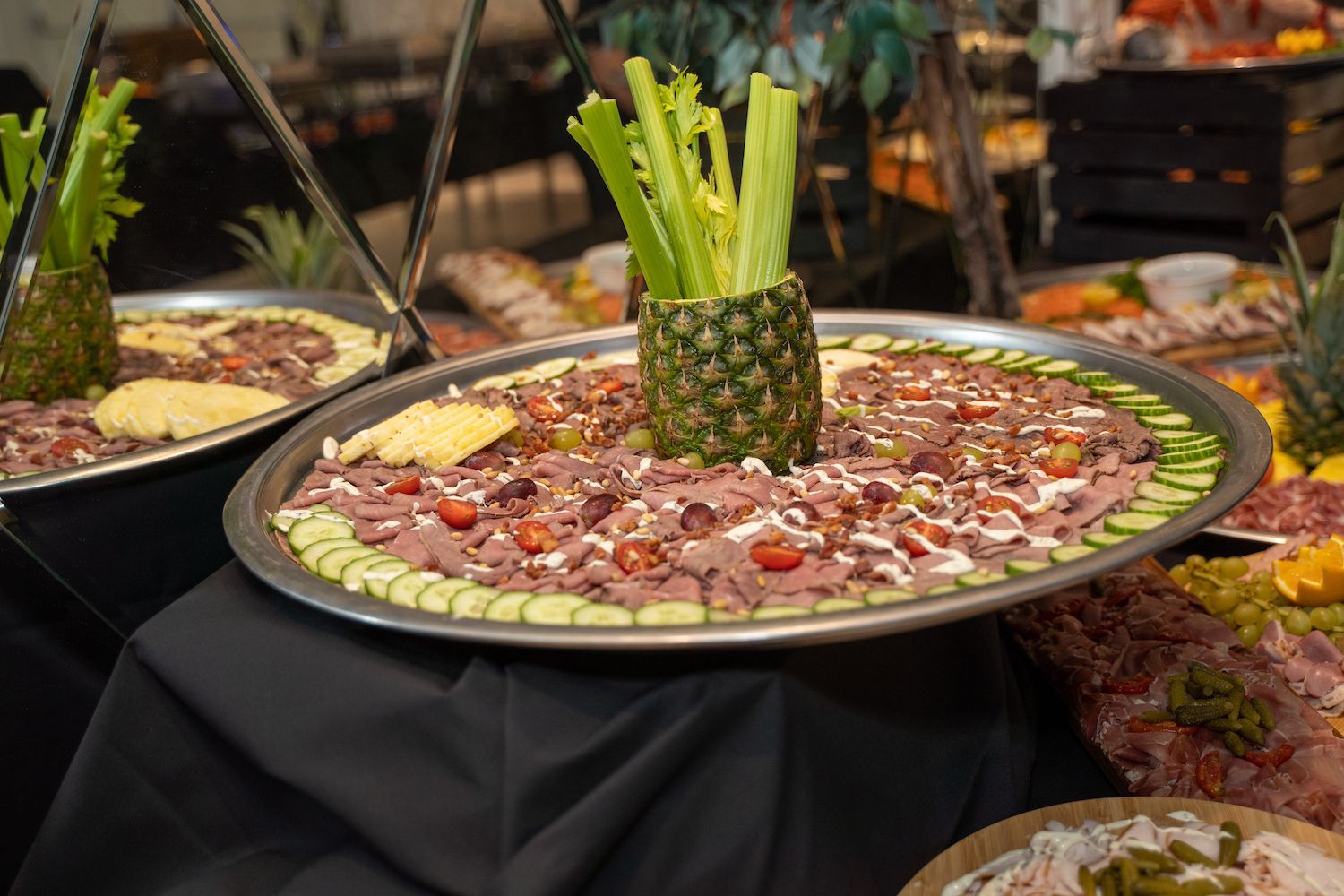 Een schotel met fruit en vlees, geserveerd in een ananas als middelpunt op een buffettafel.