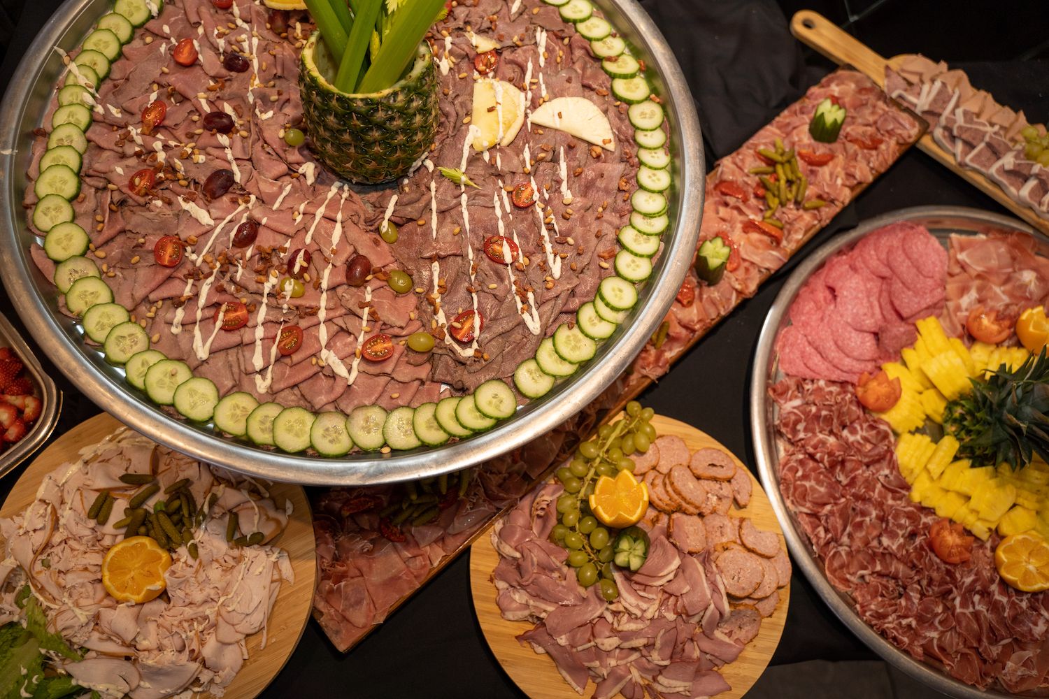Een kleurrijke Midden-Oosterse mezze-schotel met hummus, vleeswaren, augurken en garnituren op grote schalen.