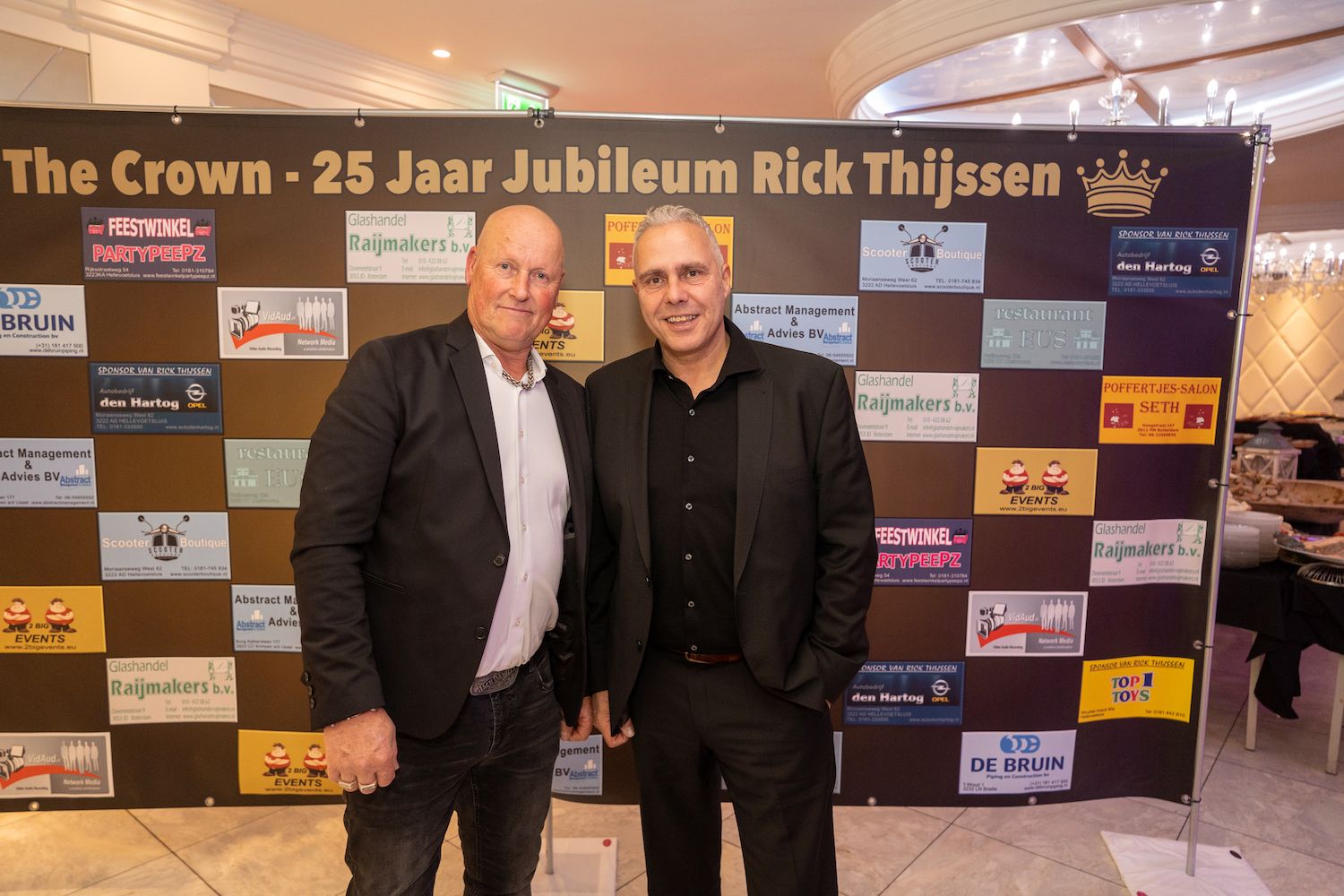 Twee mannen poseren voor een achtergrond met de tekst 