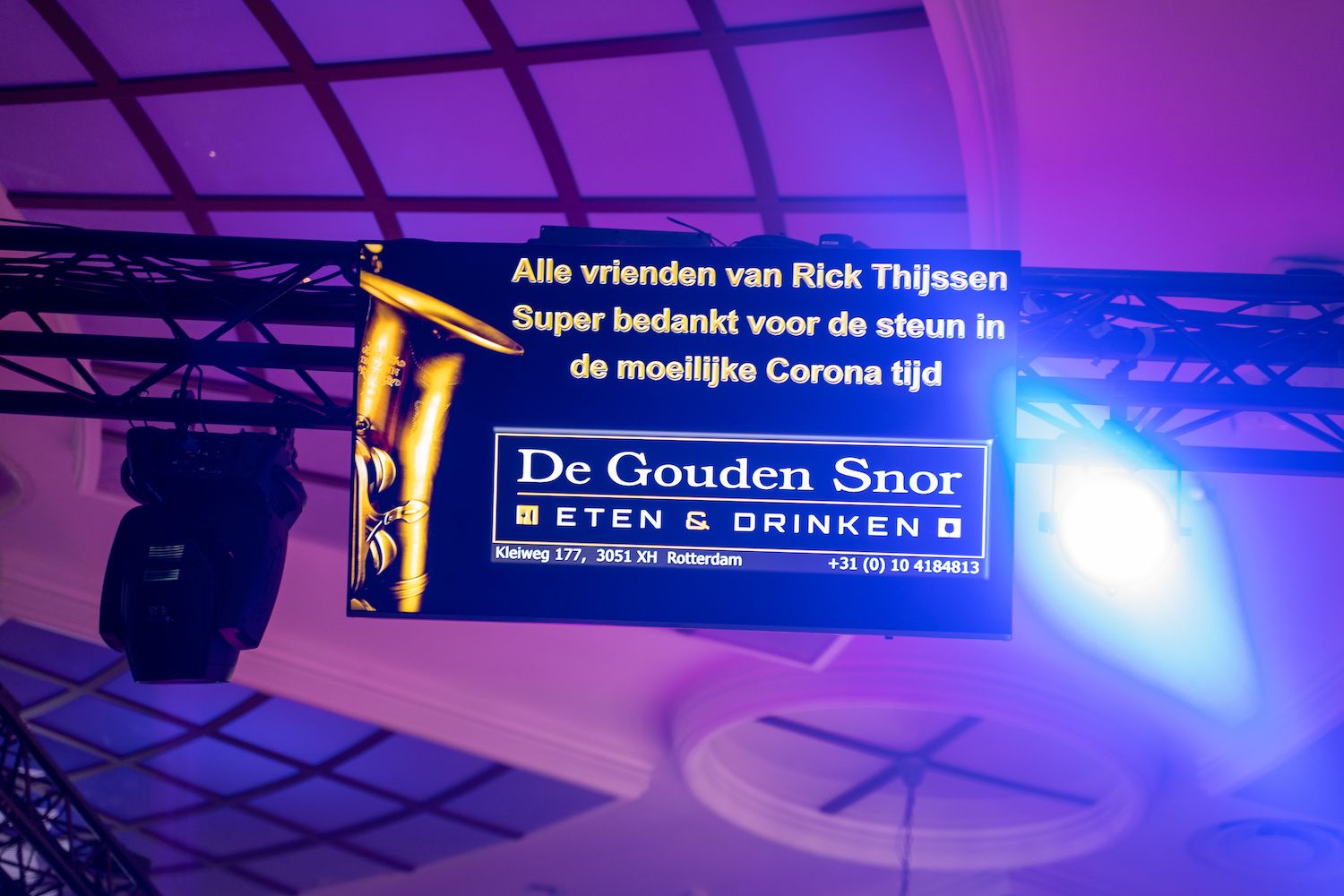 Paars verlicht reclamebord voor restaurant en bar De Gouden Snor, met Nederlandse tekst die een voorstelling aankondigt.