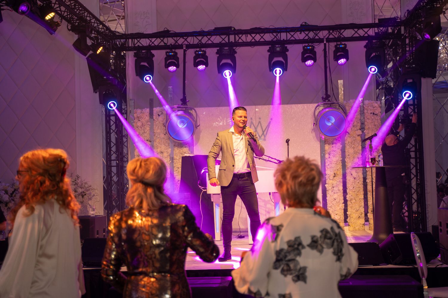 Zangeres treedt op een verlicht podium met paarse spotlights op, met haar gezicht naar het publiek.