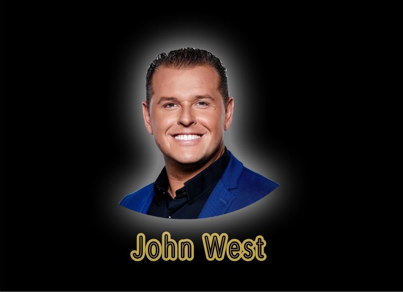 Portret van John West op een zwarte achtergrond, lachend in een blauwe jas.