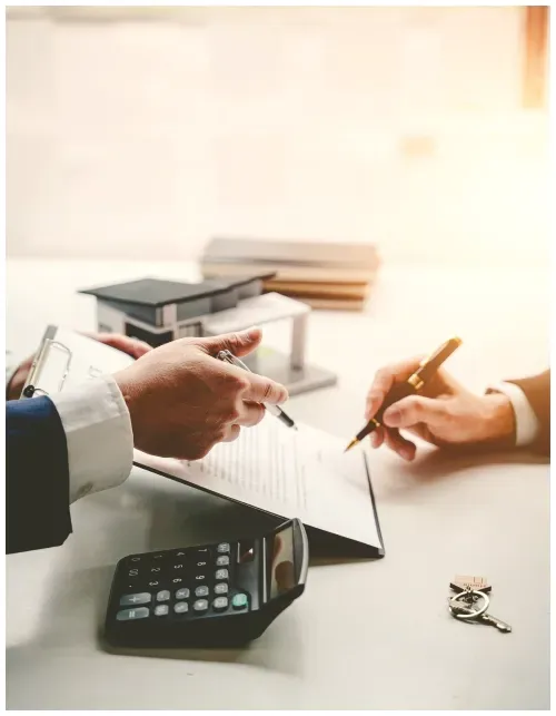 Two people are sitting at a table with a calculator and a pen.