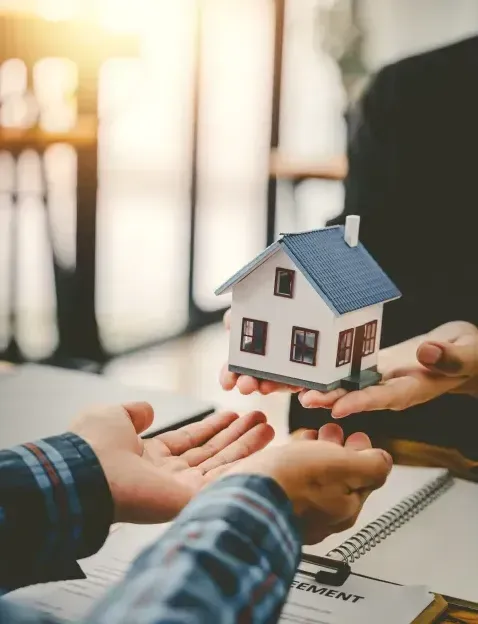 A person is holding a model house in their hands.