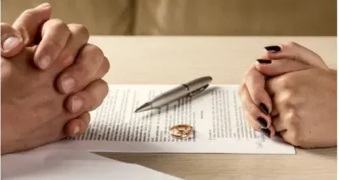 A man and a woman are sitting at a table with their hands folded.