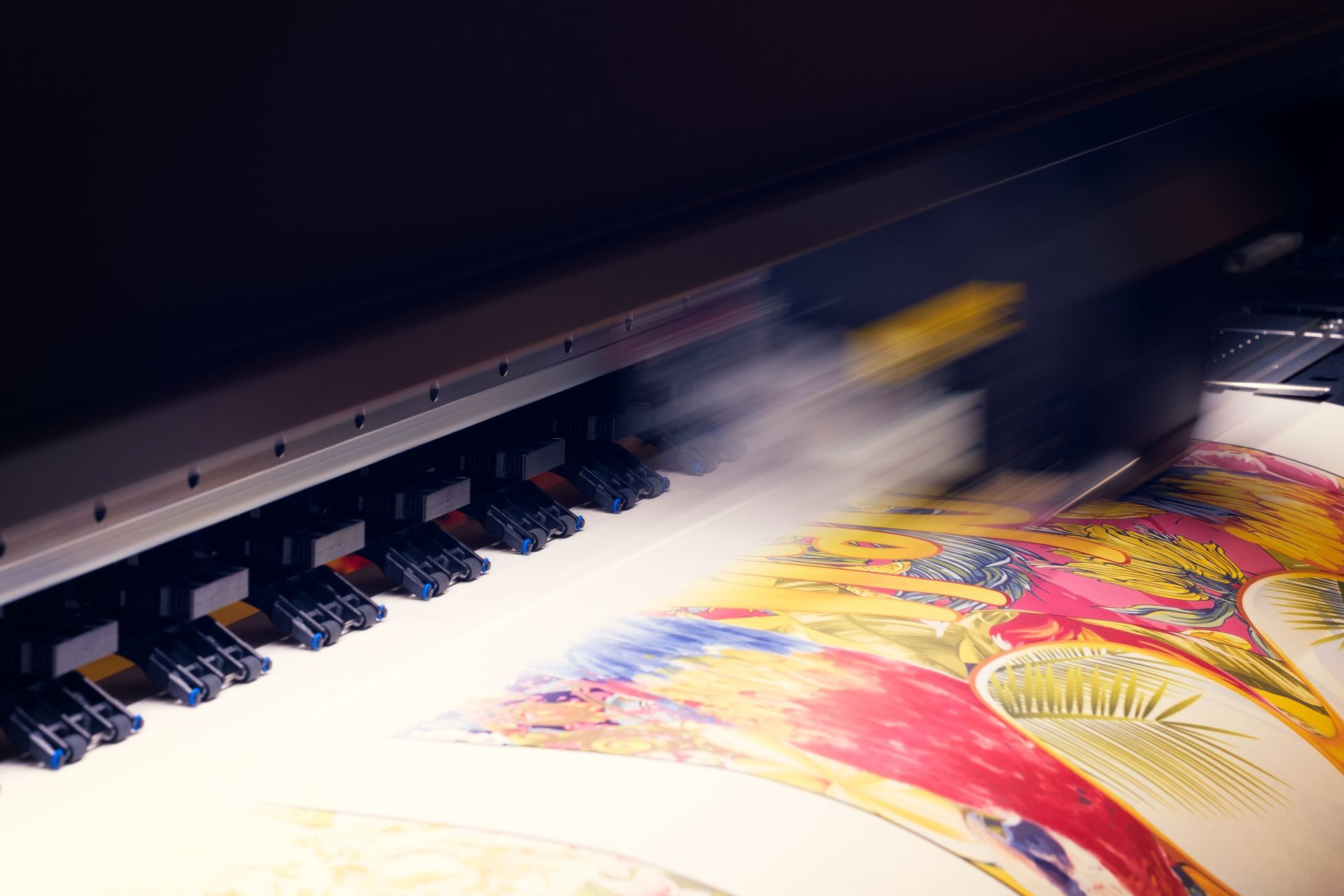 Large-format printer producing a colorful print with white ink mist over paper