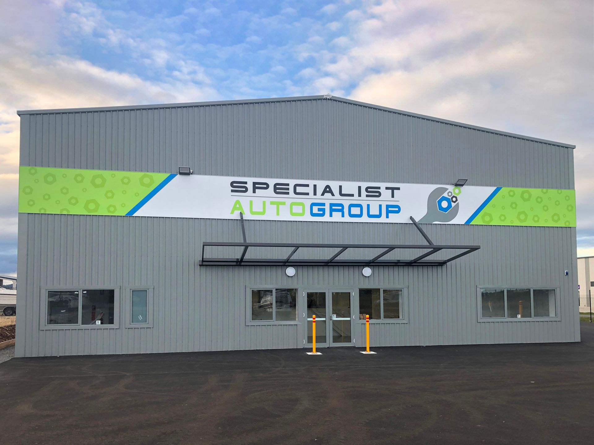Specialist Auto Group building with signage and awnings under a cloudy sky.