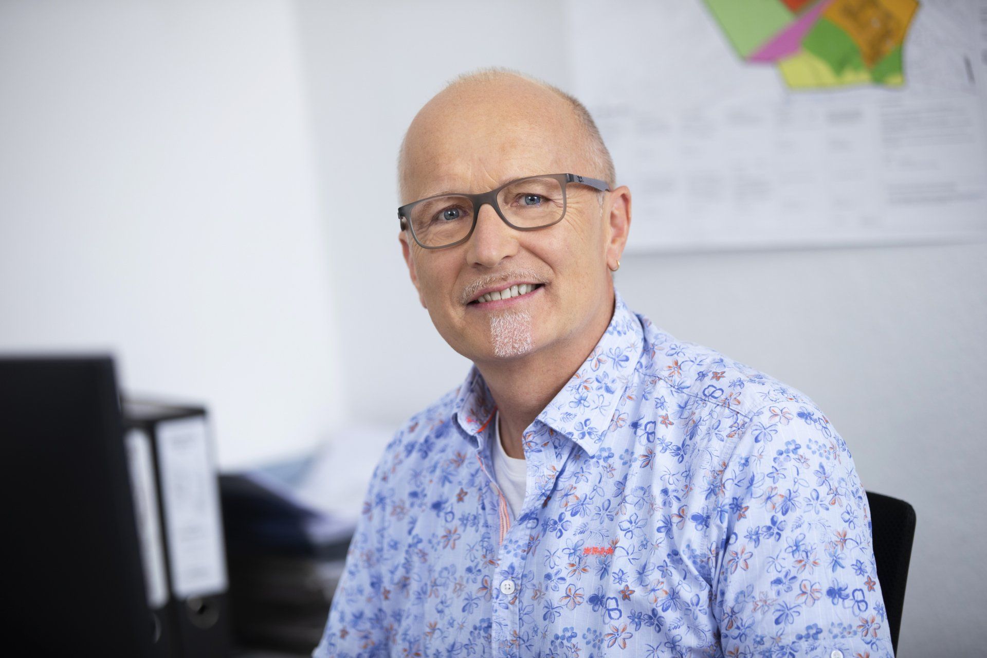 Ein Mann mit Brille sitzt an einem Schreibtisch vor einem Computer.