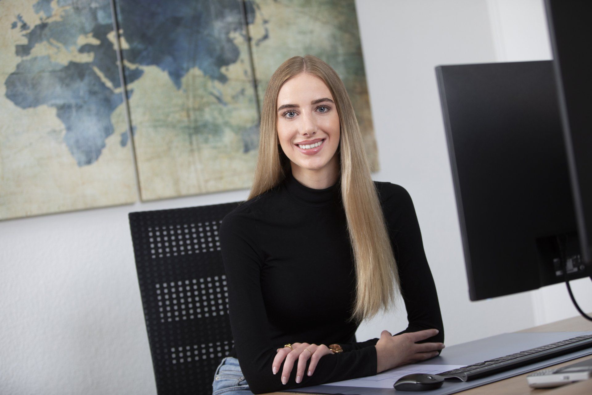 Eine Frau sitzt an einem Schreibtisch vor einem Computer.