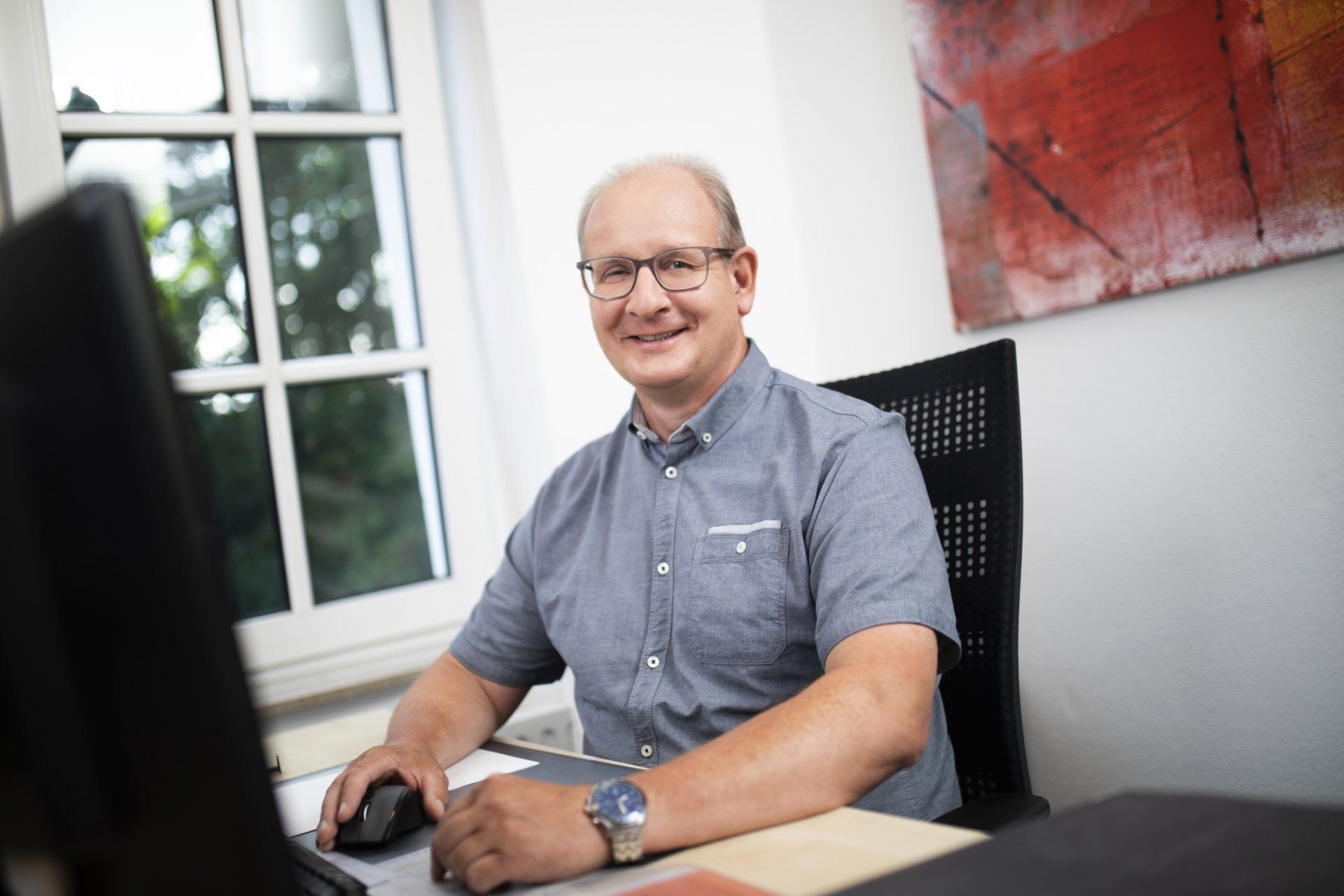 Ein Mann sitzt an einem Schreibtisch vor einem Computer.