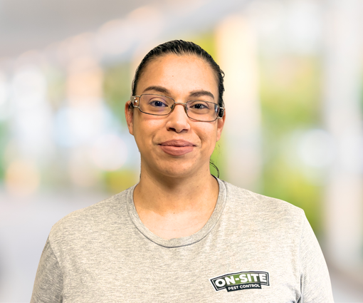 Person wearing glasses and a light gray shirt, standing against a blurred background with a slight smile.