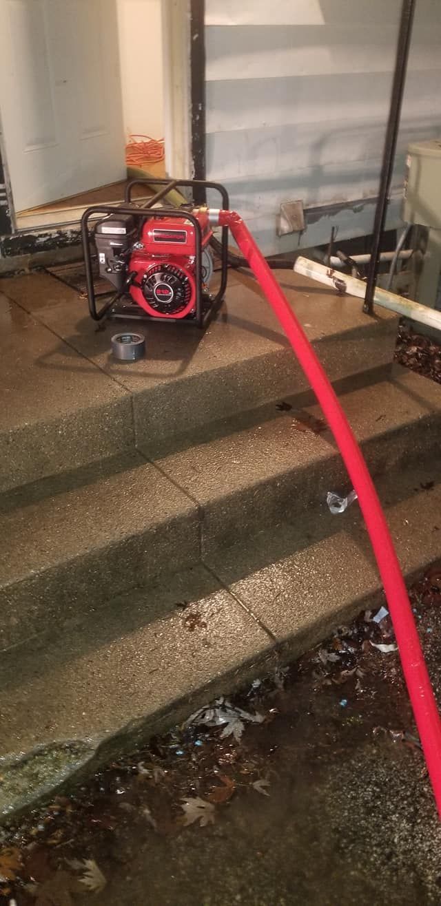 Red water pump on concrete steps with red hose. Water on steps.