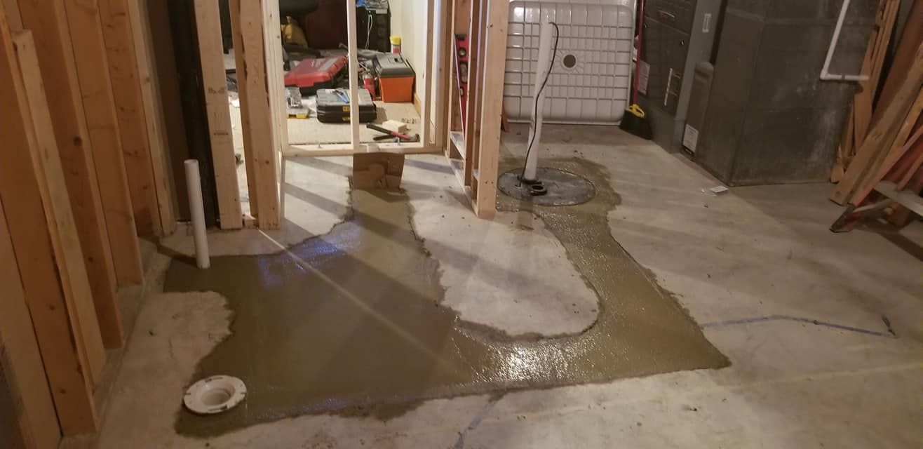 Concrete floor being poured in a room with wood framing.