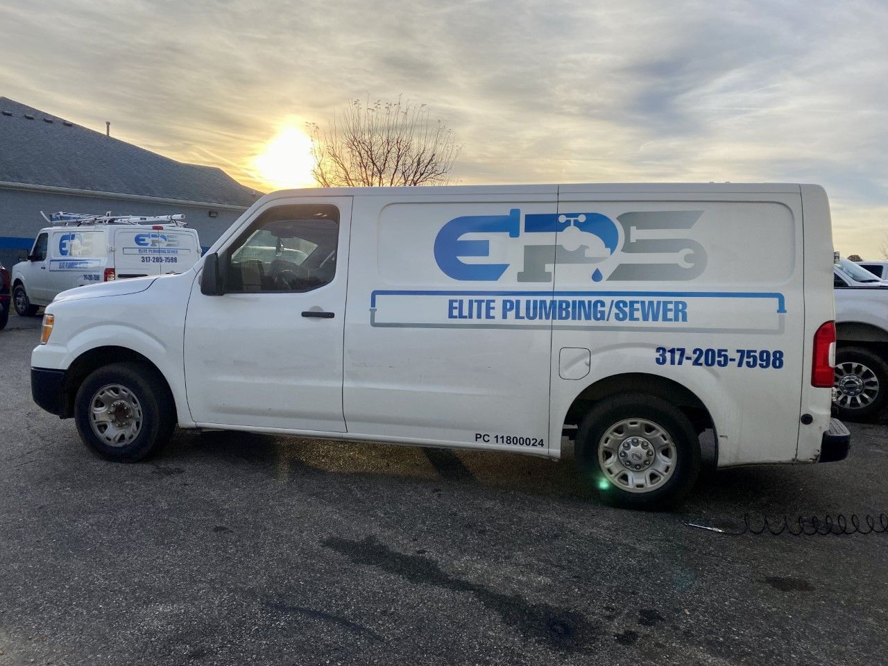White Elite Plumbing van parked outdoors with logo.