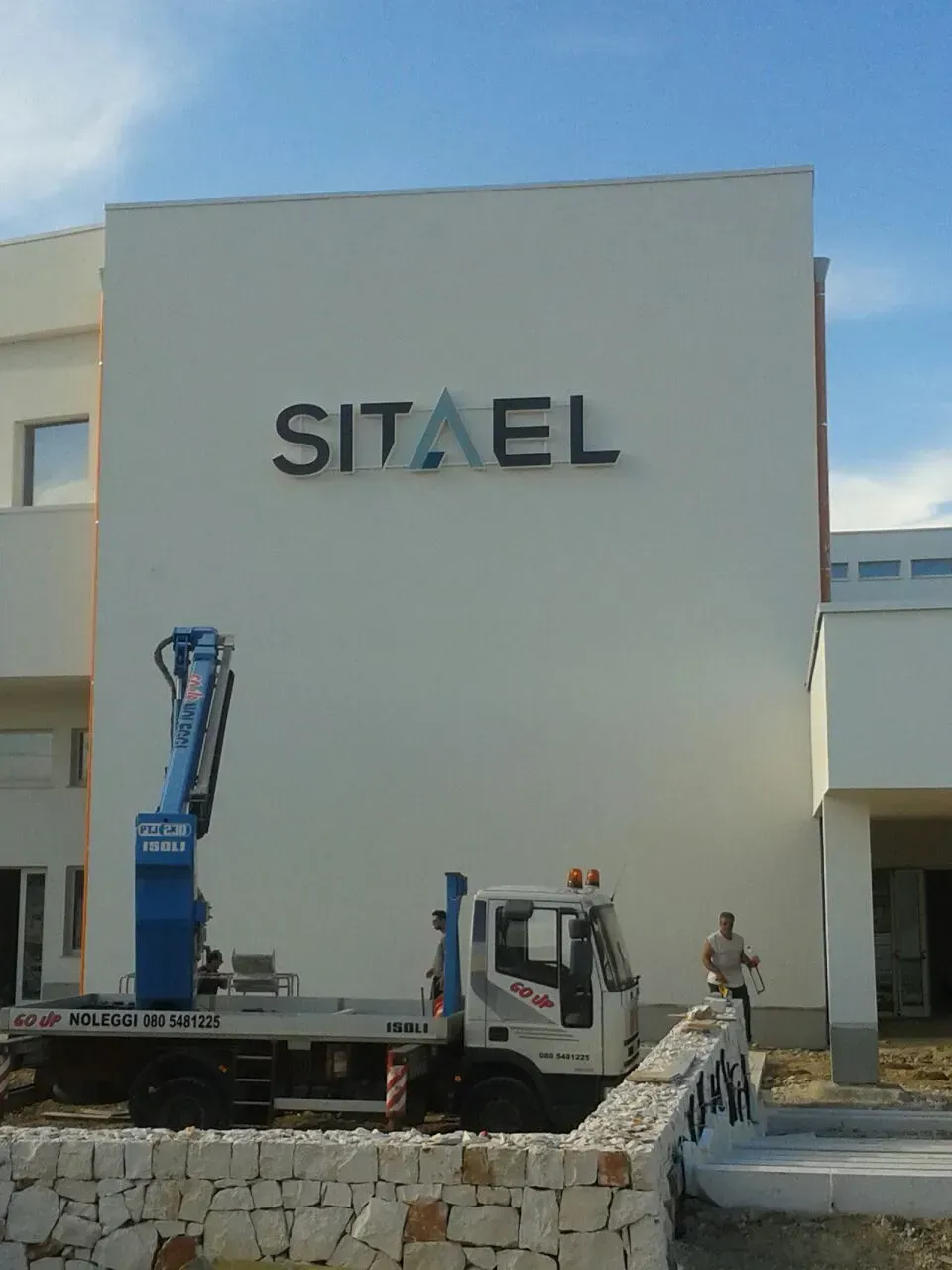 Un camion con sollevatore è parcheggiato davanti a un edificio con la scritta