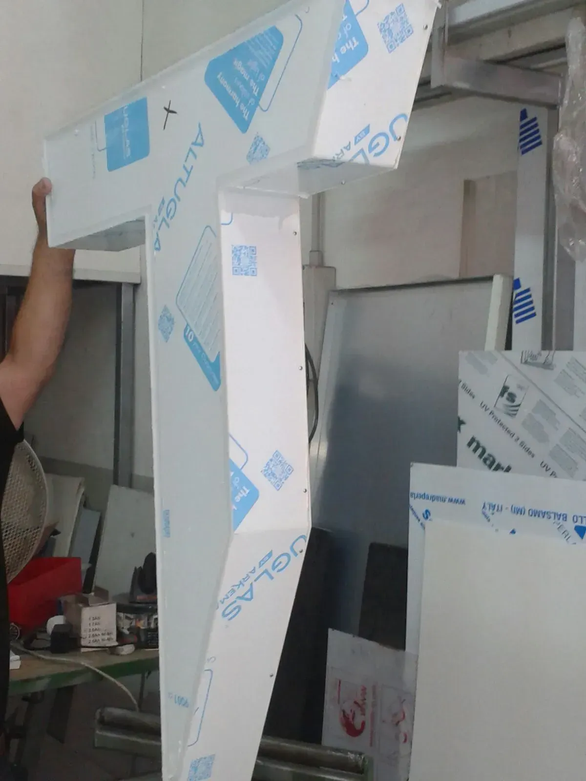 Ampia struttura in cartone espanso bianco all'interno di un'officina, con una persona parzialmente visibile sulla sinistra.