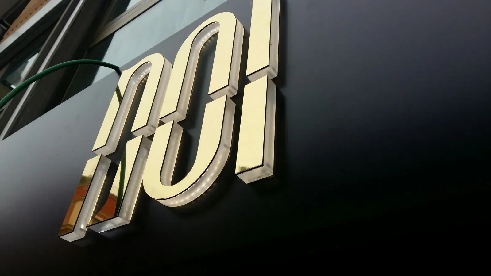 Cartello esterno con numeri “001” dorati su sfondo nero.