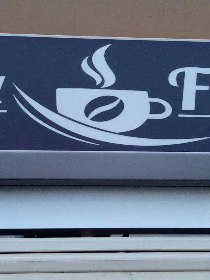 Logo di una tazza di caffè bianca con vapore su sfondo scuro.