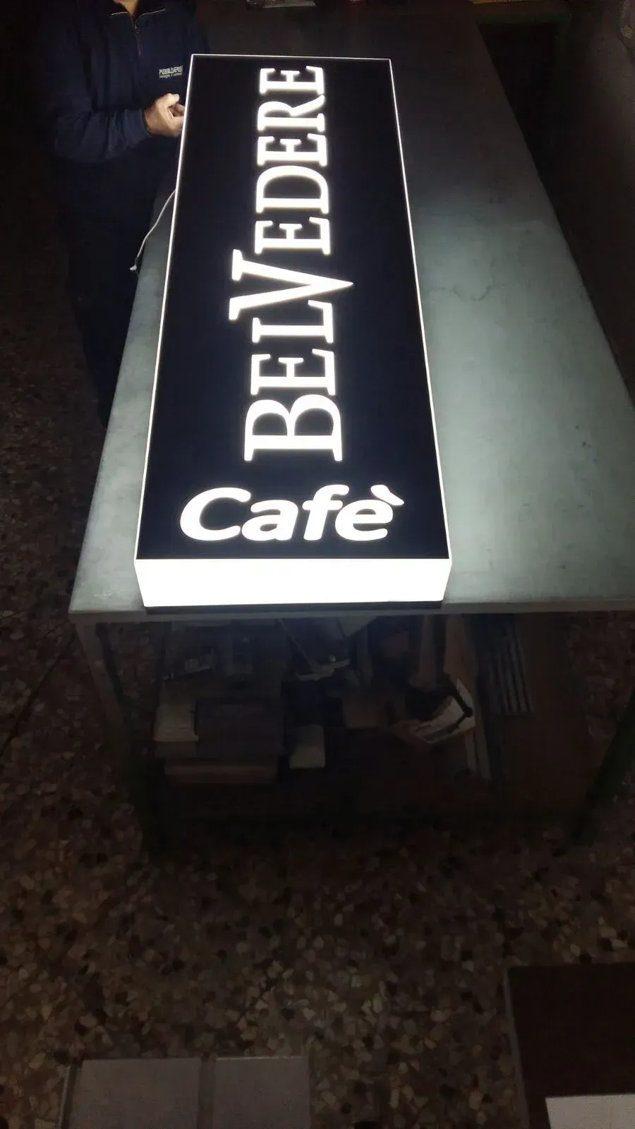 L'insegna illuminata del Belvedere Café su una vetrina buia di notte.
