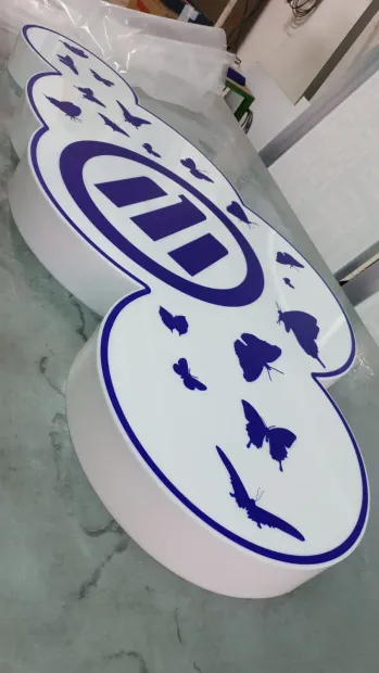Cartello bianco con grafica viola e sagome di animali, appoggiato su un pavimento all'interno.
