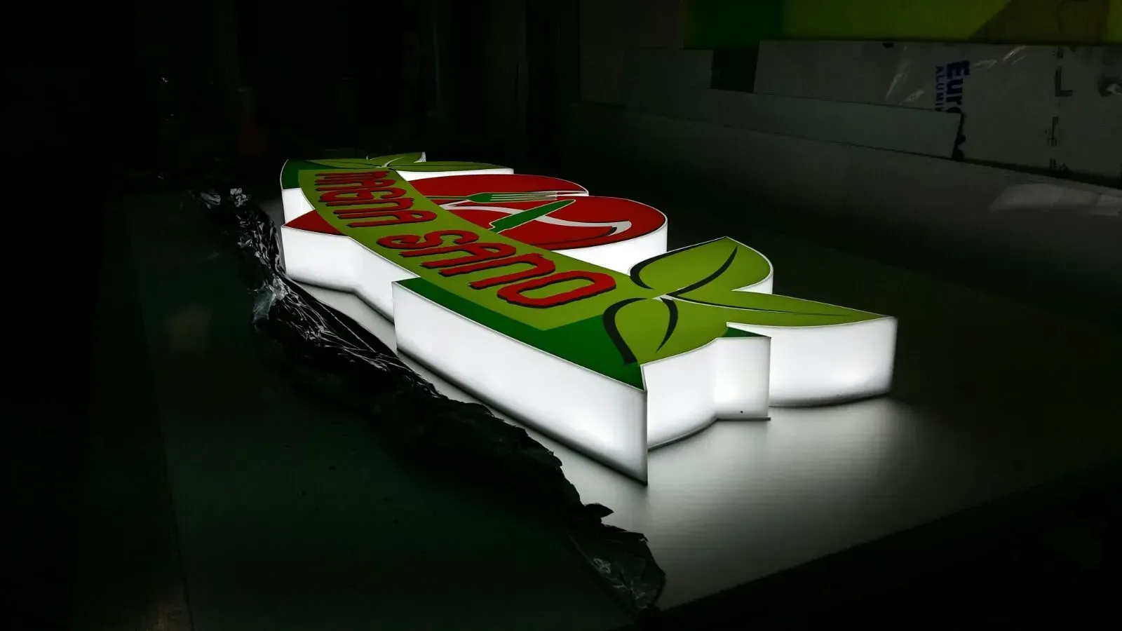 Logo Doritos in 3D su sfondo scuro, illuminato dal basso in rosso, verde, bianco e arancione.