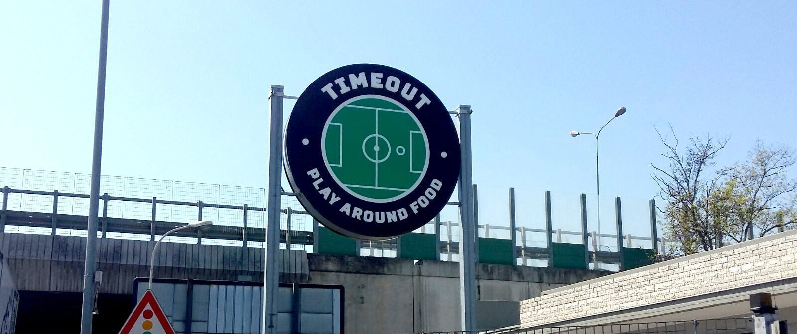 Cartello dello stadio del Toulouse FC con l'icona di un campo da calcio verde su una recinzione dello stadio sotto un cielo sereno.