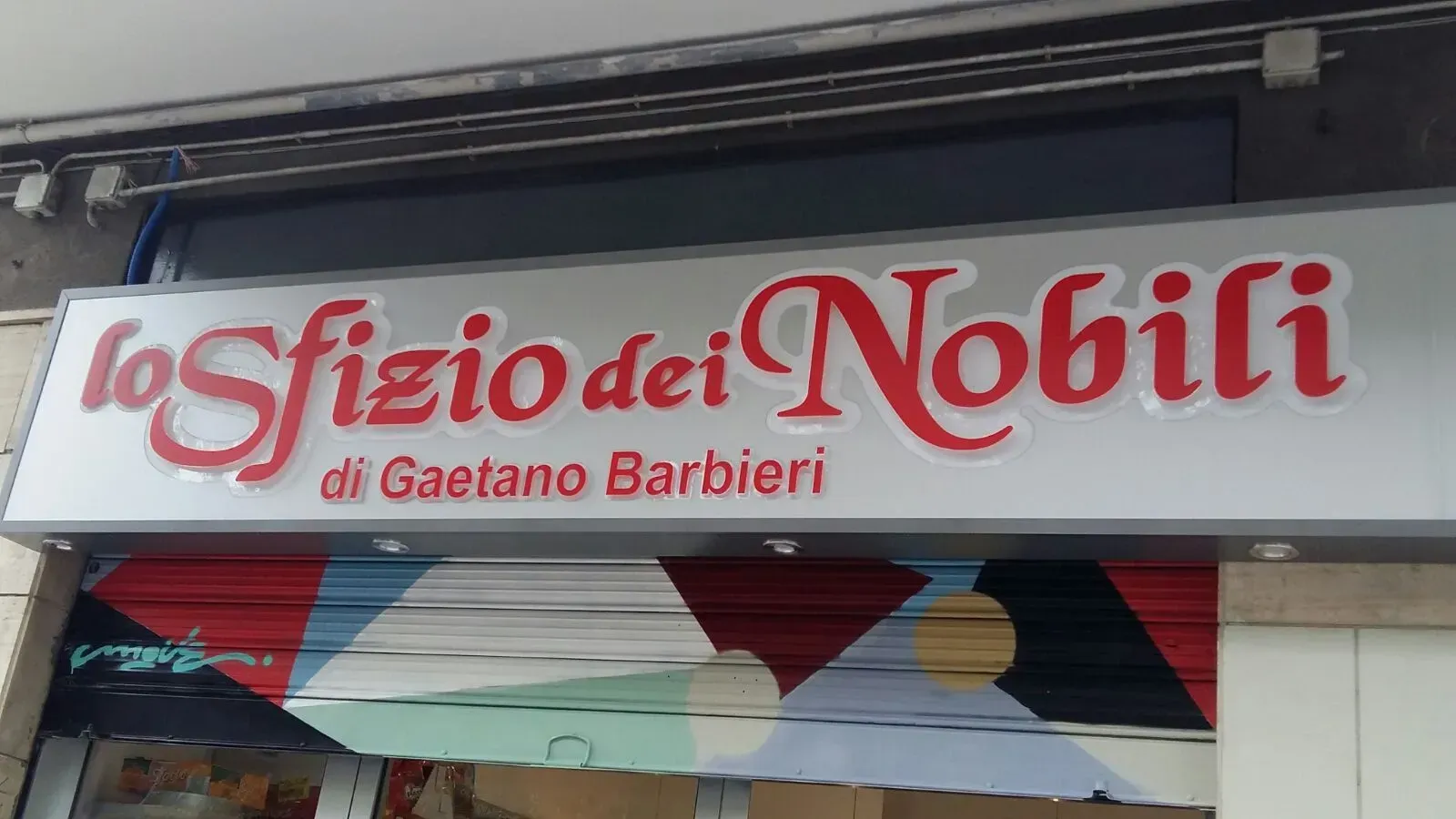 Storefront sign reading “Lo Sfizio dei Nobili” in red and white lettering.