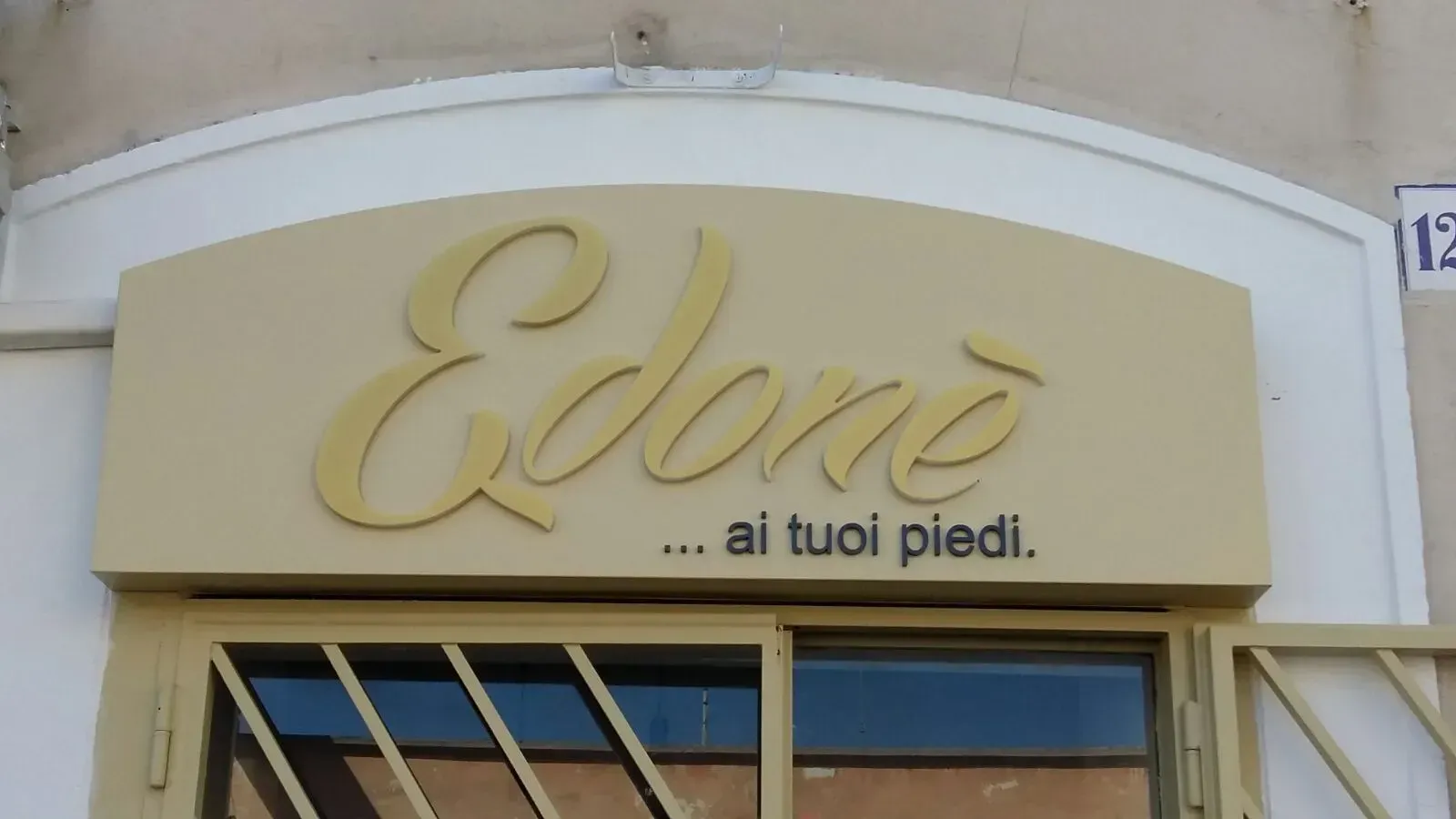 Storefront sign reading “Edoné … ai tuoi piedi” on a beige facade.
