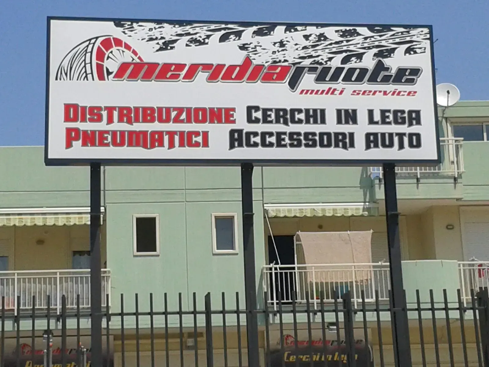 Insegna di un negozio di ricambi auto con le scritte “Amerida Auto” e “Pneumatici, accessori auto” su un edificio