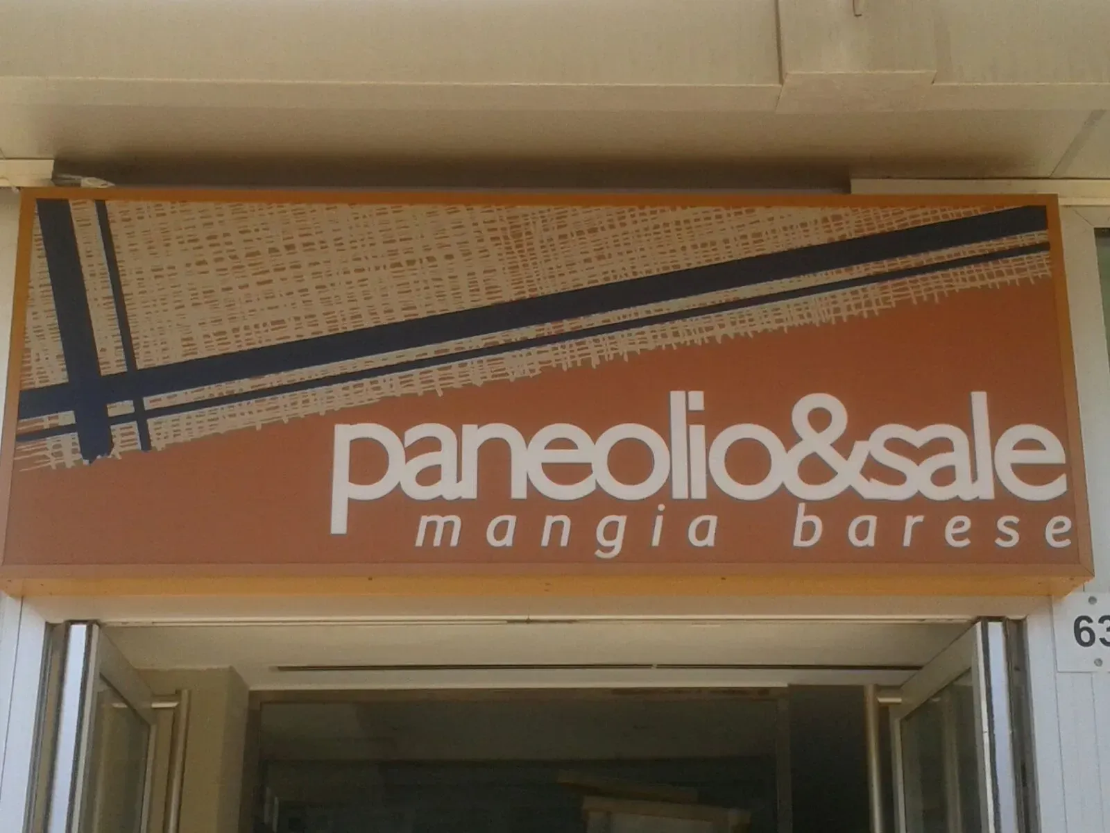 Insegna della panetteria Panela & Sale su una vetrina arancione sopra un ingresso