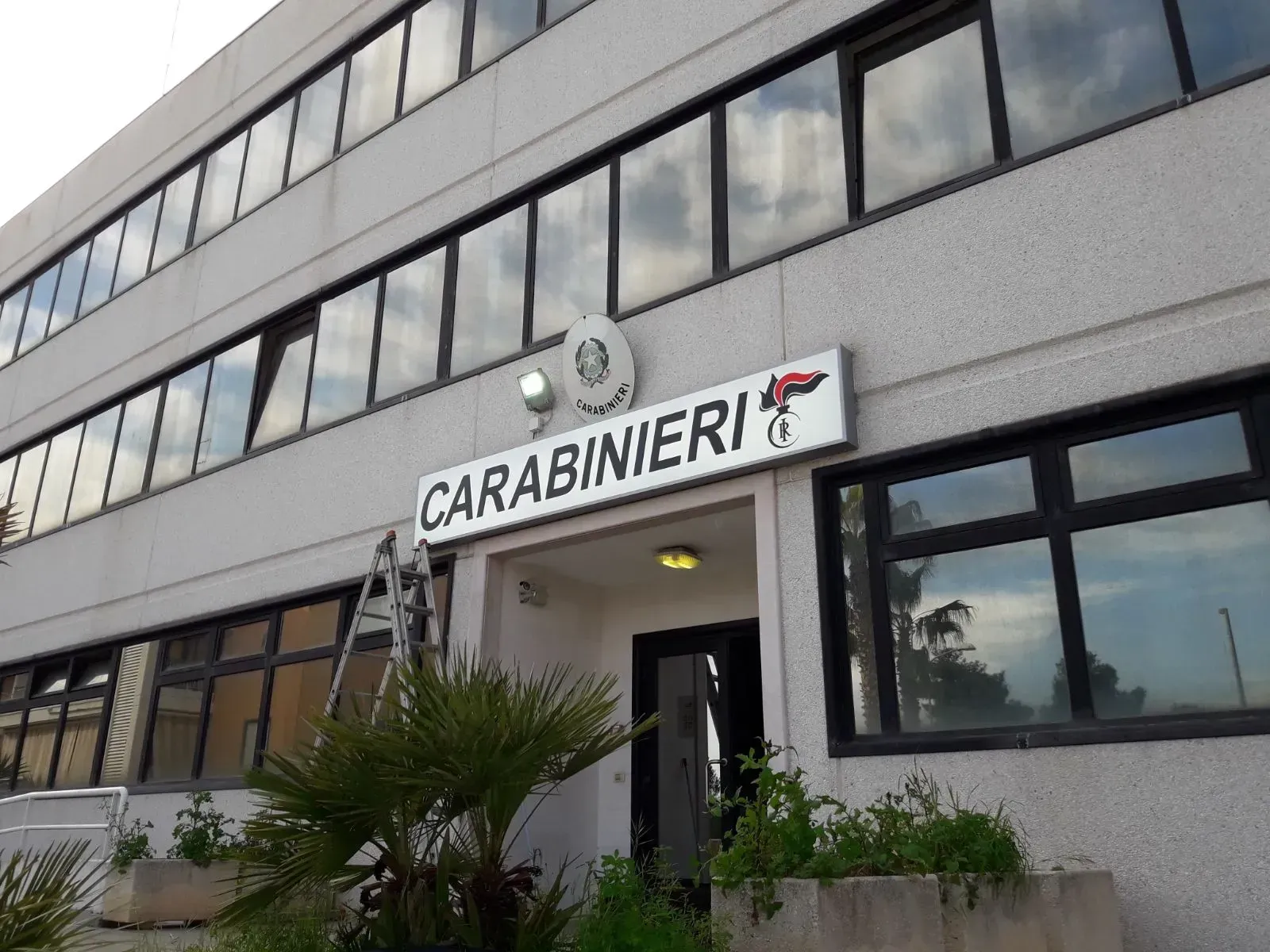 Esterno della stazione dei Carabinieri con insegna sopra l'ingresso e grandi finestre