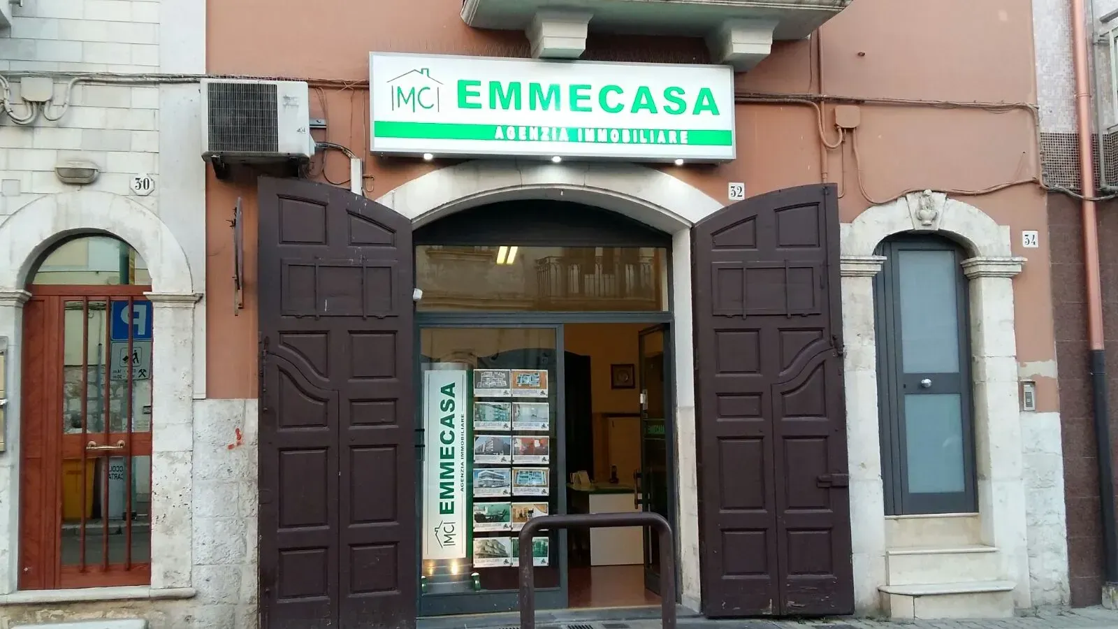 Ingresso del negozio con porte di legno aperte e un'insegna verde con la scritta