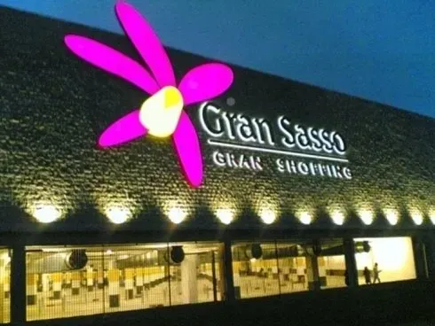 Salone e boutique Gian Sasso di notte, con insegna a forma di fiore rosa acceso e vetrine illuminate.