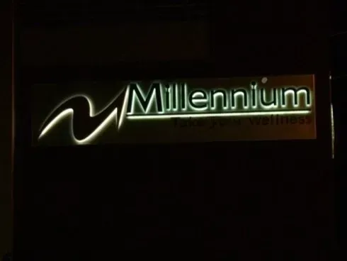 Logo illuminato del Millennio su sfondo scuro con testo bianco-verde luminoso.